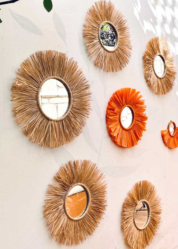A collection of sunburst rattan and orange mirrors on a white wall.